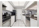 Kitchen featuring white cabinets, under cabinet range hood, an inviting chandelier, stainless steel appliances, and a sink