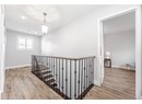 Corridor with wood finished floors, baseboards, and an upstairs landing