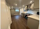Kitchen with a sink, gray cabinets, wall chimney exhaust hood, dark wood-style flooring, and appliances with stainless steel finishes