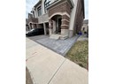 View of exterior entry with concrete driveway, brick siding, a garage, and stone siding