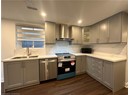 Kitchen with dark wood-style flooring, a sink, wall chimney exhaust hood, appliances with stainless steel finishes, and gray cabinets