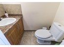 Half bath featuring toilet, vanity, tile patterned floors, and baseboards