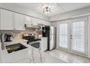 Kitchen with appliances with stainless steel finishes, under cabinet range hood, a sink, decorative backsplash, and white cabinets