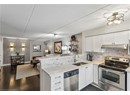 Kitchen with stainless steel appliances, a sink, under cabinet range hood, open floor plan, and backsplash