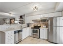 Kitchen with appliances with stainless steel finishes, under cabinet range hood, a sink, white cabinets, and backsplash
