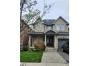 View of front of property featuring french doors, driveway, an attached garage, and brick siding