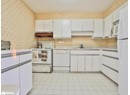 Kitchen with white appliances, under cabinet range hood, a sink, wallpapered walls, and light countertops