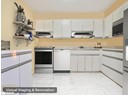 Kitchen with stainless steel appliances, under cabinet range hood, light countertops, and white cabinetry