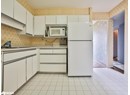 Kitchen with white appliances, wallpapered walls, light countertops, light tile patterned flooring, and white cabinetry