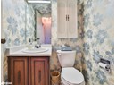 Half bath with wallpapered walls, toilet, and vanity