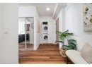 Laundry area with stacked washer / drying machine, wood finished floors, baseboards, and recessed lighting