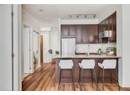 Kitchen with appliances with stainless steel finishes, dark brown cabinetry, a sink, a peninsula, and light stone countertops