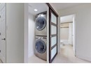 Laundry room with stacked washing machine and dryer, light tile patterned flooring, and baseboards