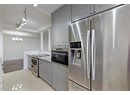 Kitchen with appliances with stainless steel finishes, gray cabinetry, light stone counters, and a chandelier