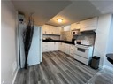 Kitchen featuring white appliances, dark countertops, backsplash, dark wood-style flooring, and white cabinetry