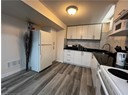 Kitchen featuring white appliances, a sink, dark wood-type flooring, a textured ceiling, and dark countertops