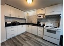 Kitchen featuring white appliances, a sink, white cabinetry, extractor fan, and a textured ceiling