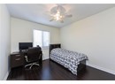 Bedroom with baseboards, dark wood-style flooring, ceiling fan, and a desk