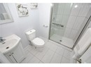 Bathroom featuring toilet, vanity, baseboards, and a shower stall