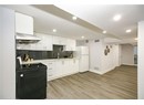 Kitchen with island range hood, a sink, black range with electric cooktop, visible vents, and freestanding refrigerator