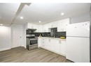 Kitchen featuring under cabinet range hood, backsplash, stainless steel electric range oven, light wood-style floors, and freestanding refrigerator