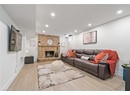 Living room featuring wood finished floors, recessed lighting, a brick fireplace, and baseboards