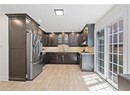 Kitchen featuring stainless steel fridge, a sink, under cabinet range hood, light stone counters, and recessed lighting
