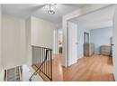 Hall featuring an upstairs landing, wood finished floors, baseboards, and a textured ceiling