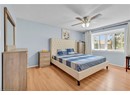 Bedroom with baseboards, light wood-style flooring, a textured ceiling, and a ceiling fan