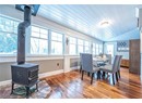 Dining area with a wood stove, a healthy amount of sunlight, wooden ceiling, and hardwood / wood-style flooring