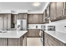 Kitchen featuring appliances with stainless steel finishes, dark brown cabinets, tasteful backsplash, a kitchen island, and wall chimney exhaust hood