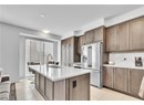 Kitchen featuring sink, high end refrigerator, light tile patterned floors, a kitchen island with sink, and decorative backsplash