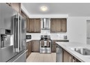 Kitchen with sink, backsplash, stainless steel appliances, dark brown cabinets, and wall chimney exhaust hood