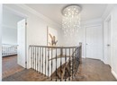 Hall with baseboards, a chandelier, an upstairs landing, and ornamental molding
