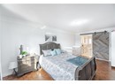 Bedroom with a barn door, a textured ceiling, baseboards, and ornamental molding