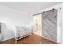 Bedroom with a barn door, baseboards, and ornamental molding