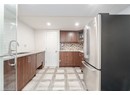Kitchen with light floors, a sink, freestanding refrigerator, glass insert cabinets, and tasteful backsplash