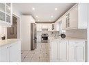 Kitchen featuring a sink, decorative backsplash, stainless steel appliances, custom range hood, and a peninsula