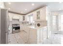 Kitchen featuring recessed lighting, stainless steel appliances, a sink, premium range hood, and light stone countertops