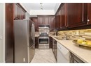 Kitchen featuring light countertops, crown molding, stainless steel appliances, under cabinet range hood, and a sink