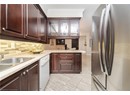 Kitchen with light countertops, crown molding, backsplash, freestanding refrigerator, and white dishwasher