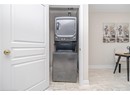 Washroom featuring marble finish floor, baseboards, stacked washer and clothes dryer, and laundry area