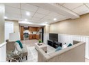 Living area with a drop ceiling, a wainscoted wall, and recessed lighting