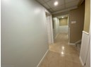 Corridor with light tile patterned flooring and a wainscoted wall