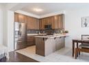 Kitchen with stainless steel appliances, a peninsula, a breakfast bar area, tasteful backsplash, and light tile patterned flooring