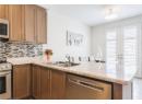 Kitchen with french doors, backsplash, a peninsula, appliances with stainless steel finishes, and light stone countertops