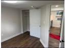 Unfurnished bedroom featuring dark wood-style flooring, freestanding refrigerator, and a closet