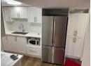 Kitchen with freestanding refrigerator, light countertops, white cabinets, and dark wood-type flooring