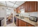Kitchen featuring stainless steel range with electric stovetop, decorative backsplash, black dishwasher, ceiling fan, and brown cabinetry