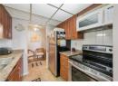 Kitchen with decorative backsplash, appliances with stainless steel finishes, brown cabinets, light tile patterned flooring, and a drop ceiling